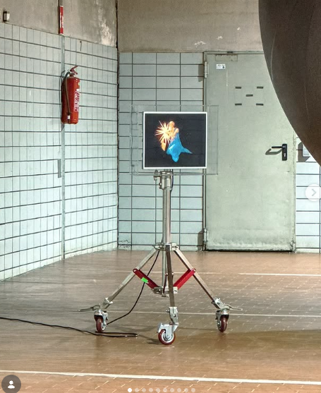 Single screen mounted on a wheeled lighting tripod in a tiled room
