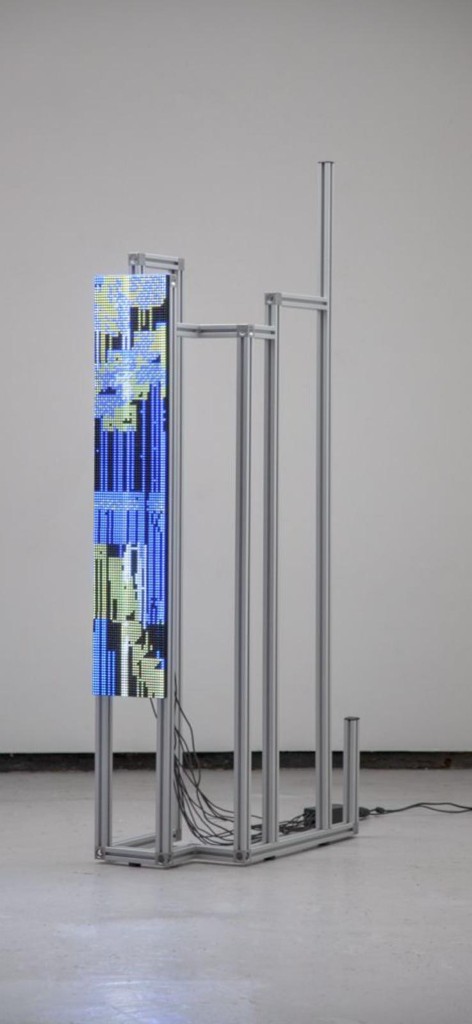 Tall stepped aluminium extrusion sculpture with a narrow illuminated display and visible cables