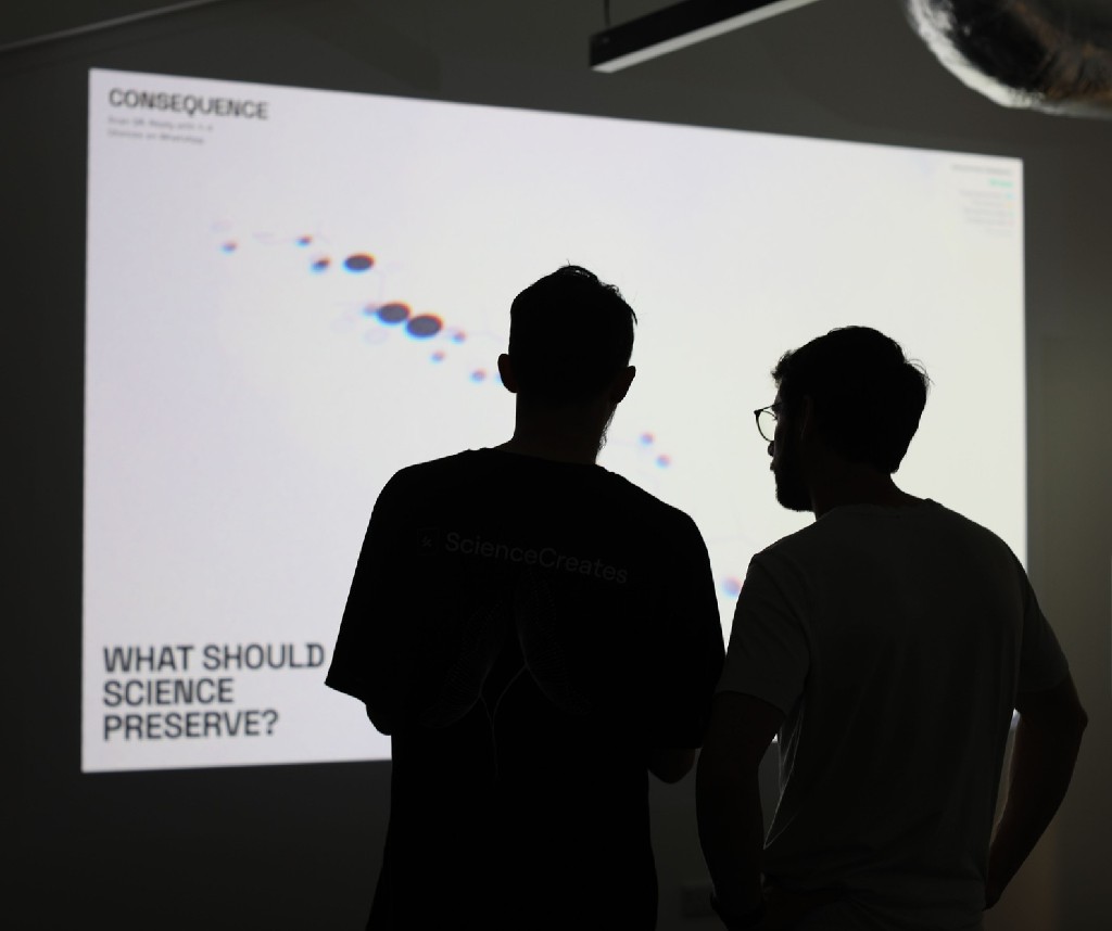 Two people at Science Creates watching Consequence projected in the room.